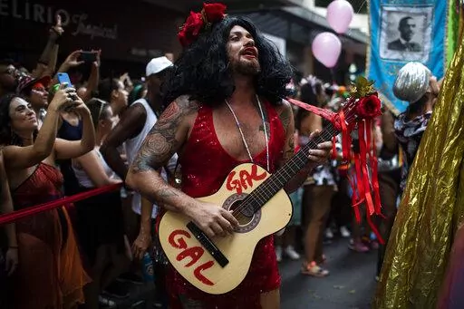 Leandro Vieira, carnival director of the Imperatriz Leopoldinense samba school, plays the guitar and wears a costume in honor of late Brazilian singer Gal Costa, during the pre-carnival parade by the Cordao do Boitata block in Rio de Janeiro, Brazil, Sunday, Feb. 12, 2023. Vieira's job includes helping pick the samba school's theme for the year, calling shots on the material for costumes and often choosing who will feature on the top of majestic floats. (AP Photo/Bruna Prado)