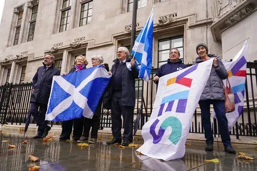 Scottish flags are held by demonstrators, outside the Supreme Court, in London, Wednesday, Nov. 23, 2022. The U.K. Supreme Court ruled Wednesday that Scotland does not have the power to hold a new referendum on independence without the consent of the British government. The judgment is a setback for the Scottish government's campaign to break away from the United Kingdom.(AP Photo/Alberto Pezzali)