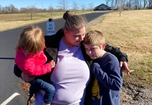 Autumn Kirks comforts her children, Sunday, Dec. 12, 2021, in Mayfield, Ky. Her boyfriend, Lannis Ward, has been missing since a tornado leveled the candle factory where they worked. (AP Photo/Bruce Schreiner)