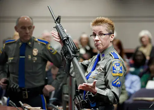 Firearms training unit Det. Barbara J. Mattson, of the Connecticut State Police, holds up a Bushmaster AR-15 rifle, the same make and model of gun used by Adam Lanza in the December 2012 Sandy Hook School shooting, during a hearing of a legislative subcommittee in Hartford, Conn., on Jan. 28, 2013. Citing a U.S. Supreme Court decision earlier this year, gun rights groups and firearms owners filed a new lawsuit Thursday, Sept. 29, 2022, in federal court in another attempt to overturn Connecticut'
