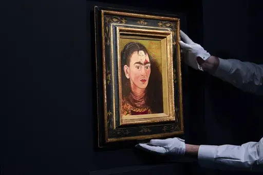 An art handler adjusts Frida Kahlo's “Diego and I” on display at Sotheby's auction house during a press preview for the Modern Evening auction, Nov. 5, 2021, in New York. The 70th anniversary of Kahlo’s death is on July 13, 2024. (AP Photo/Mary Altaffer, File)