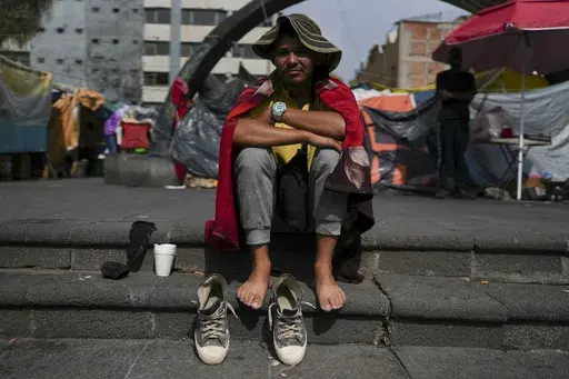 Venezuelan migrant Cristo Perez, 33, sits in the sun at a migrant camp outside the Church of La Soledad in Mexico City, Wednesday, July 31, 2024. (AP Photo/Marco Ugarte)