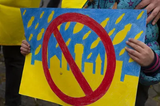 A child holds a drawing as she and others demonstrate in support of the Ukraine outside the United Nations' top court in The Hague, Netherlands, Wednesday, March 16, 2022, where judges where expected to rule on a request by Ukraine to order Russia to halt its devastating invasion. But it remains to be seen if Moscow would comply with any order made by the International Court of Justice. Russia snubbed a hearing last week at which lawyers for Ukraine accused the country's powerful neighbor of "re