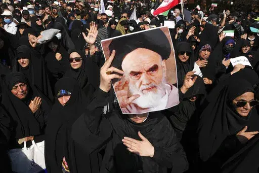 A pro-government demonstrator holds a poster of the late Iranian revolutionary founder Ayatollah Khomeini while attending a rally after the Friday prayers to condemn recent anti-government protests over the death of a young woman in police custody, in Tehran, Iran, Friday, Sept. 23, 2022. The crisis unfolding in Iran began as a public outpouring over the the death of Mahsa Amini, a young woman from a northwestern Kurdish town who was arrested by the country's morality police in Tehran last week 