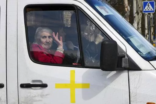 An elderly woman waves from a bus as civillians are evacuated, in Kramatorsk, Ukraine, Saturday, April 9, 2022. (AP Photo/Andriy Andriyenko)